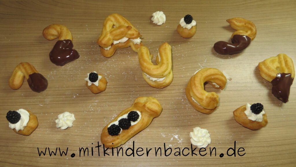 Buchstaben und Zahlen aus Brandteig mit Sahne, Schokolade und Brombeeren zum Schulanfang